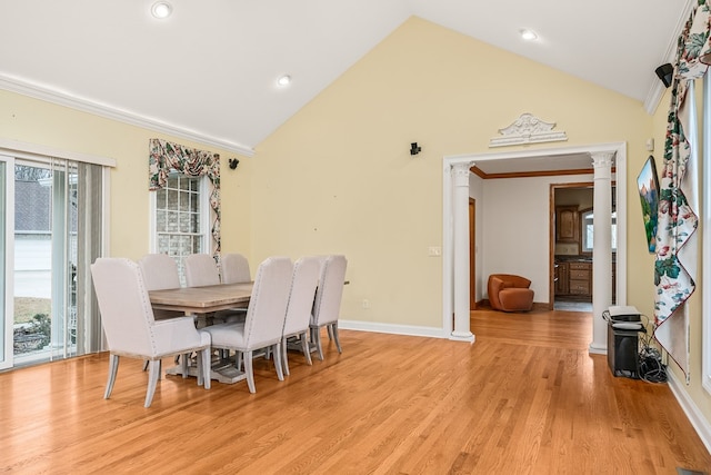 dining room with high vaulted ceiling, light wood finished floors, baseboards, and crown molding