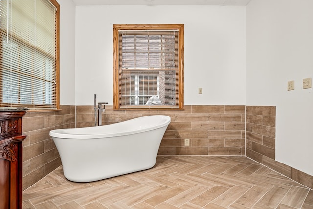 full bath featuring wainscoting, a freestanding bath, tile walls, and vanity