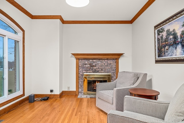 sitting room with ornamental molding, light wood-type flooring, a brick fireplace, and baseboards