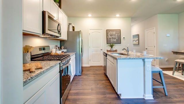 218 Dale Mires Ln, Baxter, TN 38544 - kitchen with stainless steel appliances, a sink, a center island with sink, a kitchen breakfast bar, and dark wood finished floors