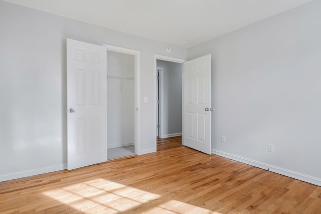 unfurnished bedroom featuring baseboards, a closet, and light wood-style floors