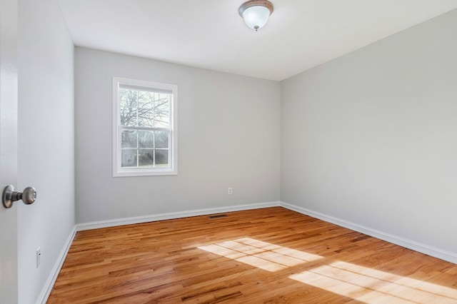 empty room featuring light wood-type flooring, visible vents, and baseboards