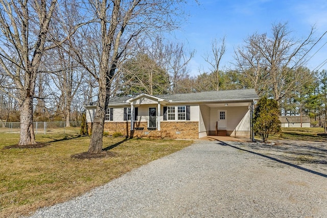 single story home featuring brick siding, a front yard, fence, a carport, and driveway