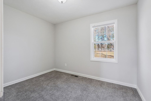 empty room with carpet flooring, visible vents, and baseboards