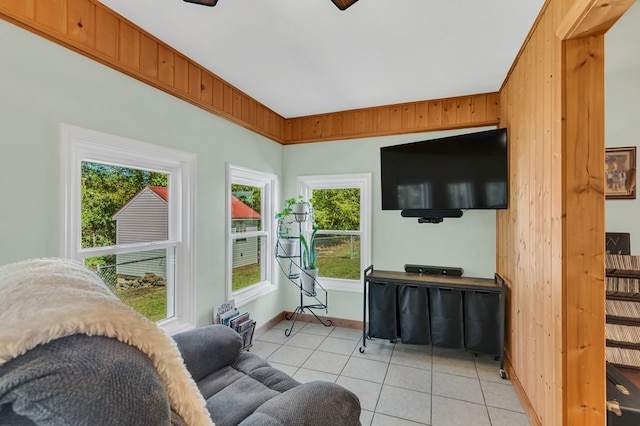 living area with wooden walls, baseboards, and light tile patterned flooring