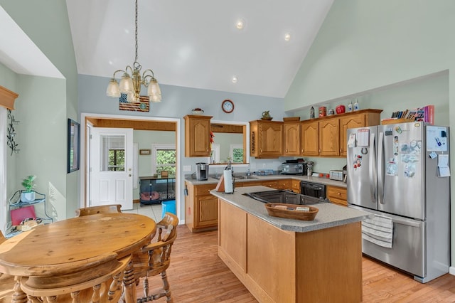 kitchen with light wood finished floors, a kitchen island, decorative light fixtures, light countertops, and black appliances