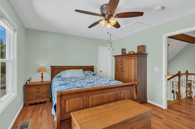 bedroom with light wood finished floors, attic access, visible vents, and baseboards