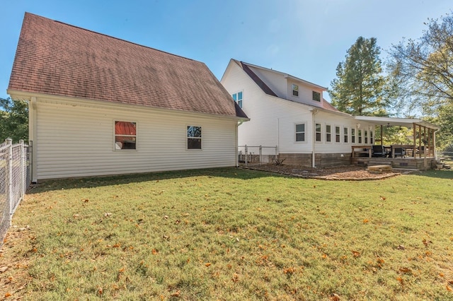 rear view of house featuring a patio area, a shingled roof, fence, and a lawn