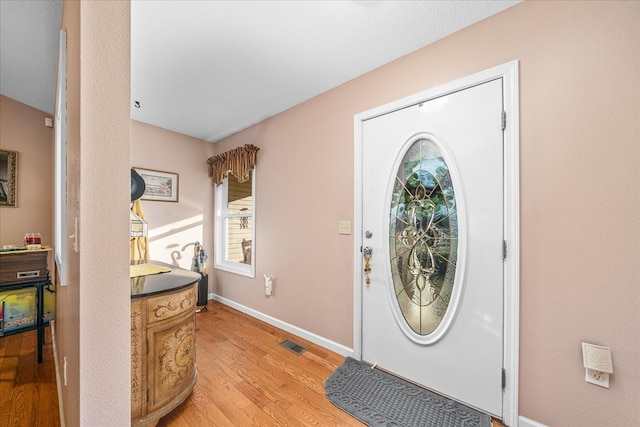 foyer featuring baseboards, visible vents, and light wood finished floors