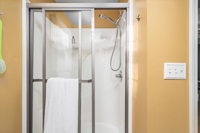 bathroom featuring a textured wall and a stall shower