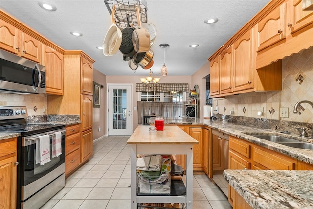 kitchen featuring light tile patterned floors, stainless steel appliances, wood counters, a sink, and decorative light fixtures