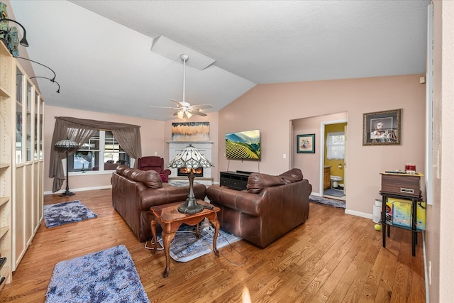 living room featuring lofted ceiling, ceiling fan, wood finished floors, and baseboards