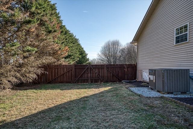 view of yard featuring a gate, central AC unit, and fence