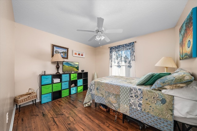 bedroom featuring dark wood-type flooring, a textured ceiling, and a ceiling fan