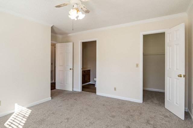 unfurnished bedroom featuring ornamental molding, a walk in closet, light carpet, and baseboards