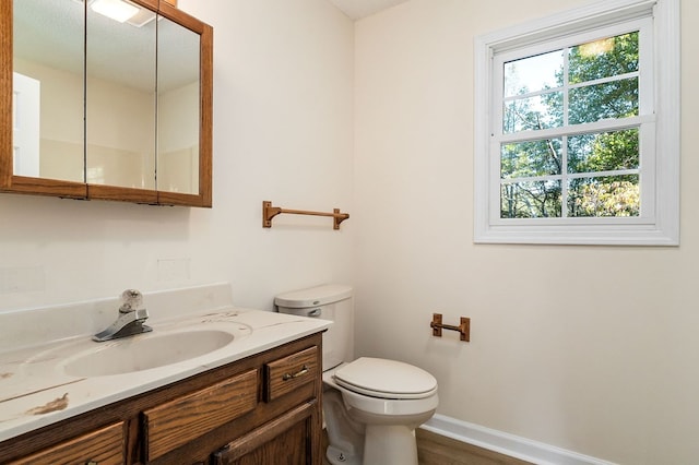 bathroom featuring baseboards, vanity, and toilet