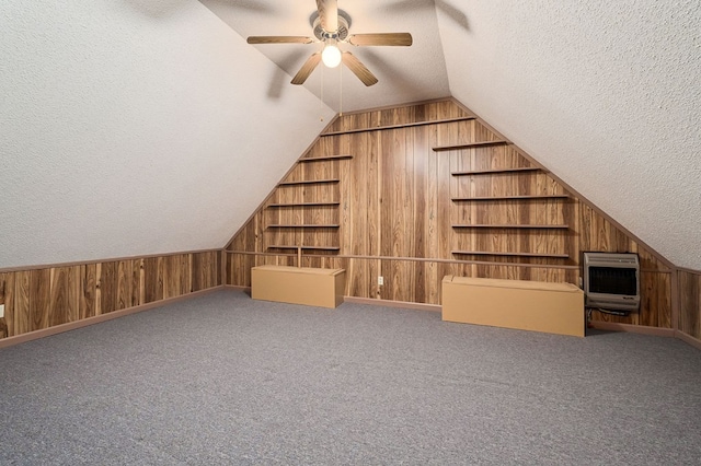 bonus room featuring a textured ceiling, built in shelves, wooden walls, vaulted ceiling, and heating unit