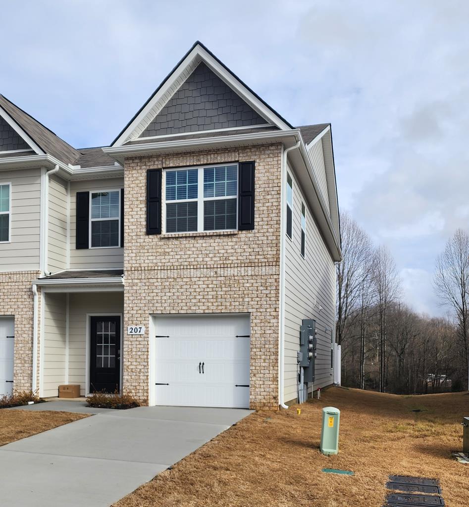 view of front of home with brick siding, driveway, and an attached garage