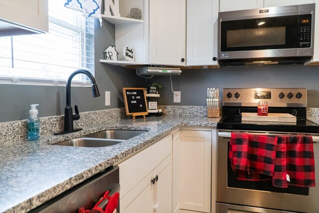 kitchen with open shelves, appliances with stainless steel finishes, a sink, and white cabinets