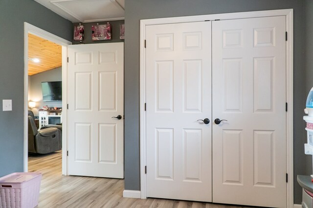 bedroom with light wood-style flooring, baseboards, and a closet