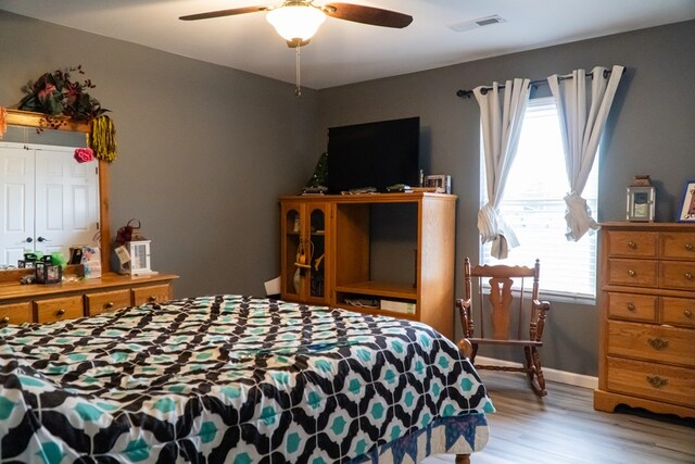 bedroom with light wood-style floors, visible vents, baseboards, and a ceiling fan