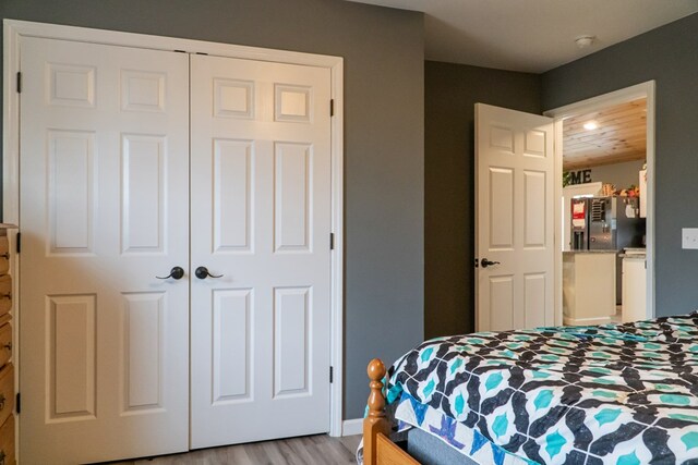 bedroom with stainless steel refrigerator with ice dispenser, a closet, and light wood-type flooring