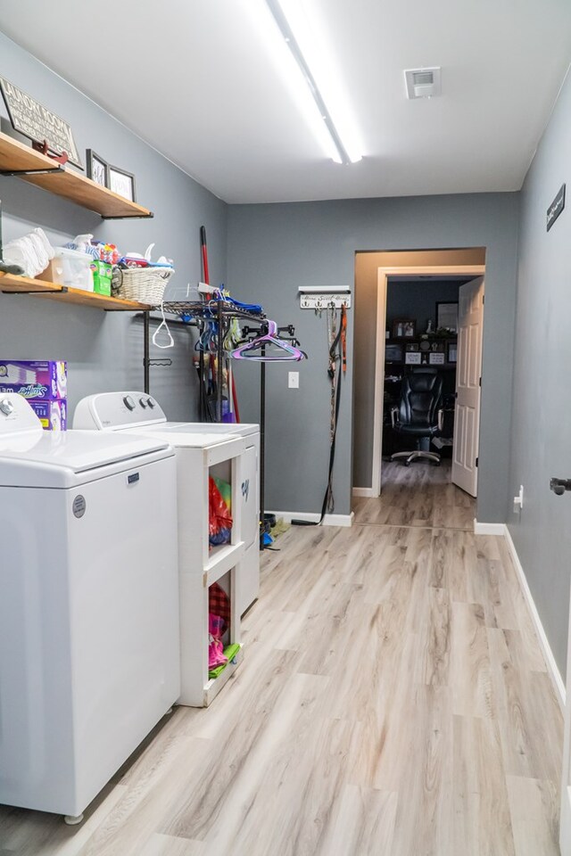 washroom featuring washing machine and clothes dryer, visible vents, light wood-style flooring, laundry area, and baseboards