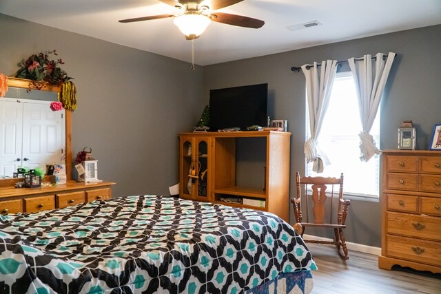 bedroom with light wood-style flooring, visible vents, ceiling fan, and baseboards