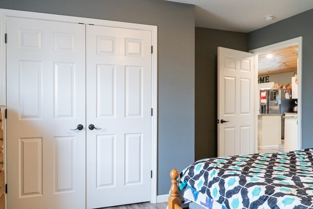 bedroom with a closet and stainless steel refrigerator with ice dispenser