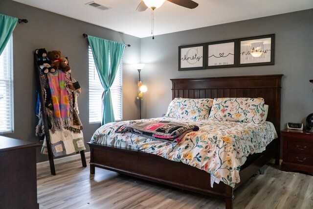 bedroom featuring baseboards, wood finished floors, visible vents, and a ceiling fan