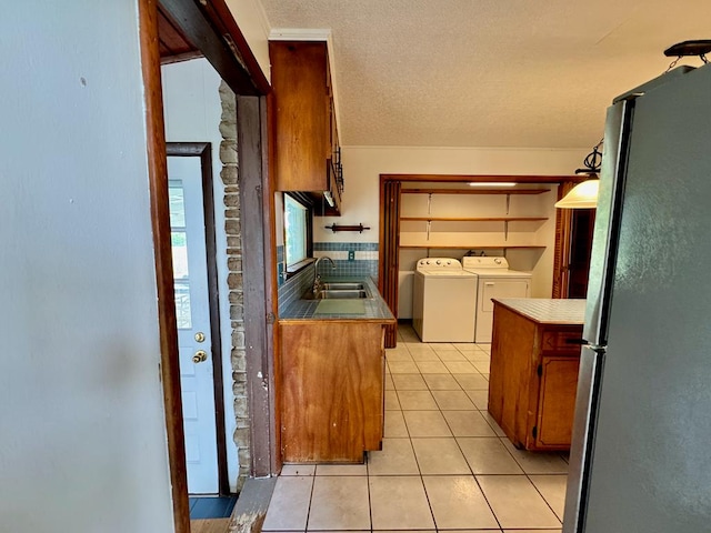 1039 Old Martha Washington Rd, Clarkrange, TN 38553 - kitchen with freestanding refrigerator, washing machine and clothes dryer, light tile patterned flooring, brown cabinetry, and a textured ceiling