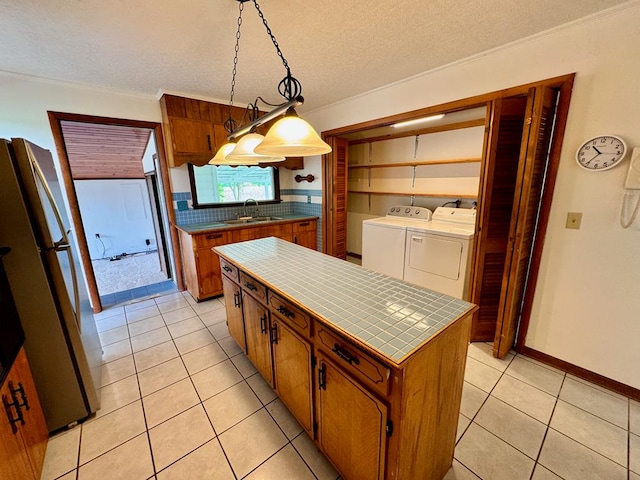 1039 Old Martha Washington Rd, Clarkrange, TN 38553 - kitchen with washing machine and clothes dryer, tile countertops, freestanding refrigerator, brown cabinets, and backsplash