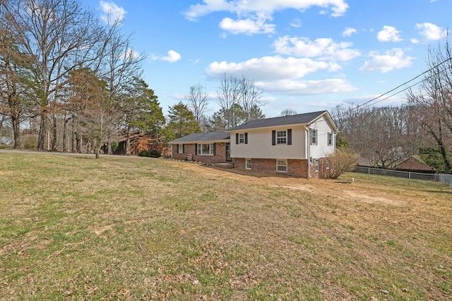 exterior space featuring brick siding, a lawn, and fence