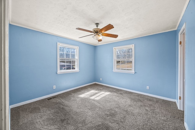 carpeted spare room featuring visible vents, crown molding, baseboards, ceiling fan, and a textured ceiling