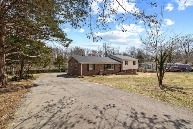 view of front of house with brick siding, driveway, and a front yard