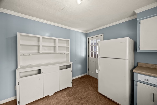 kitchen featuring white cabinetry, baseboards, a textured ceiling, and freestanding refrigerator