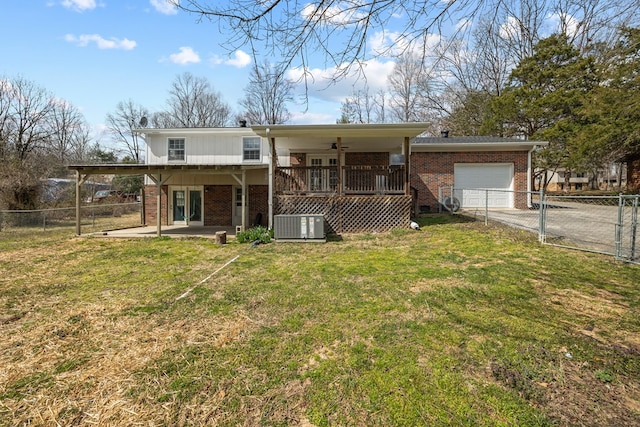 rear view of house with a garage, brick siding, a yard, and a ceiling fan