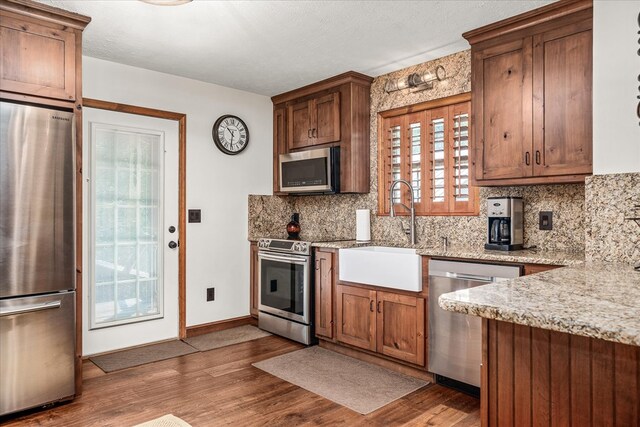 kitchen featuring a sink, decorative backsplash, appliances with stainless steel finishes, and wood finished floors