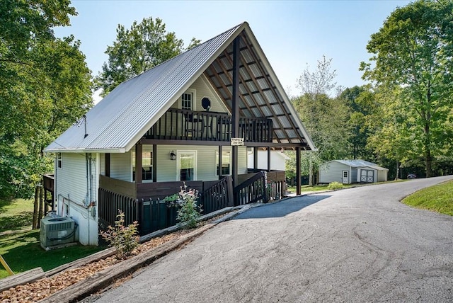 view of front of property featuring an outbuilding, central air condition unit, a porch, metal roof, and a shed