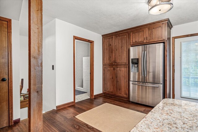 kitchen with dark wood-style floors, stainless steel fridge, a textured ceiling, and baseboards