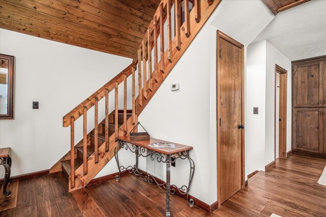 stairway featuring lofted ceiling, baseboards, and wood-type flooring