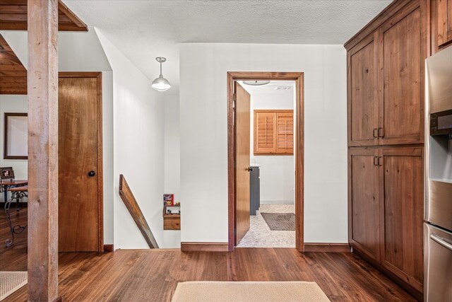 corridor with a textured ceiling, dark wood-type flooring, and baseboards