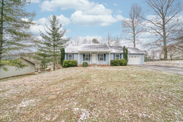 view of front of house featuring aphalt driveway, covered porch, a front lawn, and a garage