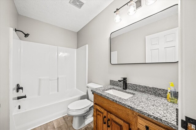 full bathroom featuring a textured ceiling, toilet, wood finished floors, vanity, and visible vents