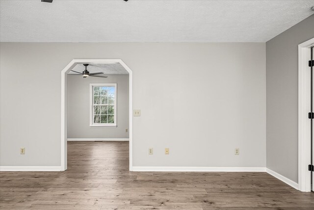 empty room with baseboards, dark wood finished floors, and a ceiling fan