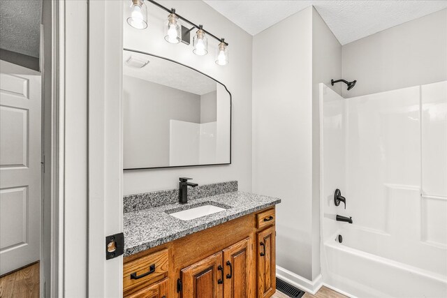 bathroom featuring shower / washtub combination, visible vents, a textured ceiling, vanity, and baseboards