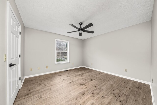 spare room with ceiling fan, a textured ceiling, wood finished floors, and baseboards