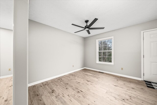 empty room featuring light wood finished floors, visible vents, ceiling fan, a textured ceiling, and baseboards