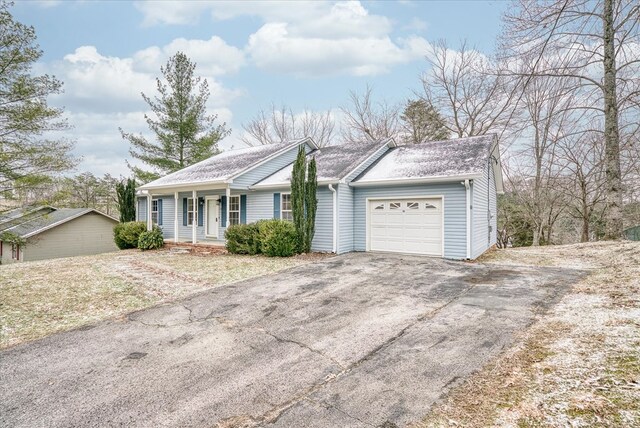 ranch-style house with covered porch, driveway, roof with shingles, and an attached garage