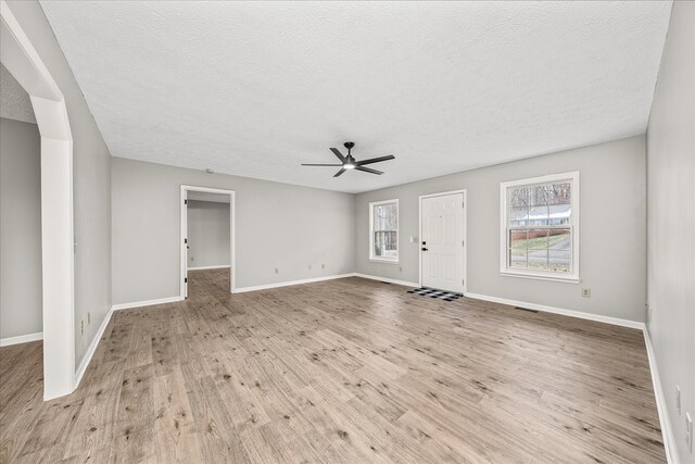 unfurnished living room with ceiling fan, baseboards, and light wood-style floors